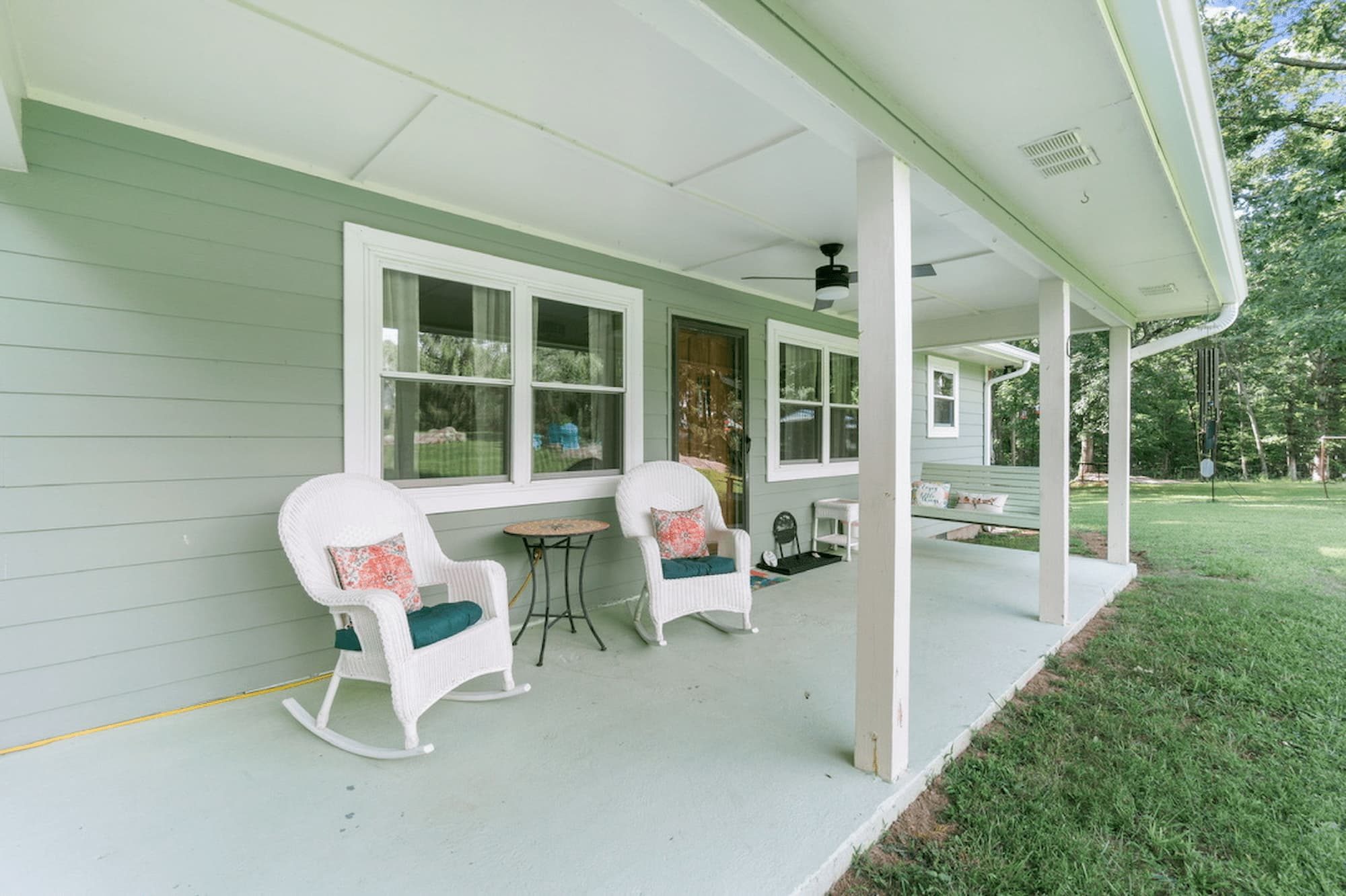 Covered front porch with white wicker rocking chairs and a porch swing